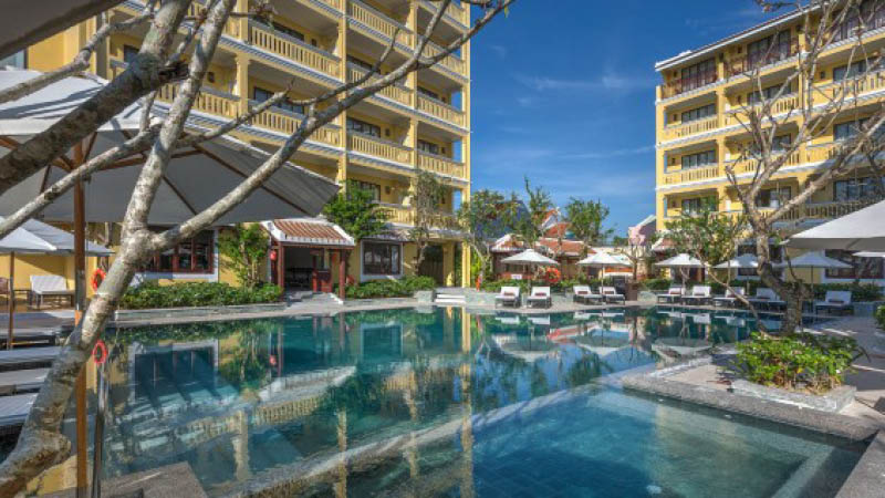 Stor utomhuspool bland vxter och solstolar p hotell Little hoian Central Boutique & spa i Hoi An, Vietnam.